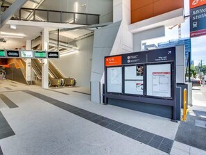 A modern train station platform with escalators, a digital information board, and a clear walkway. - Entire rental unit in Paddington, Australia (Paddington)