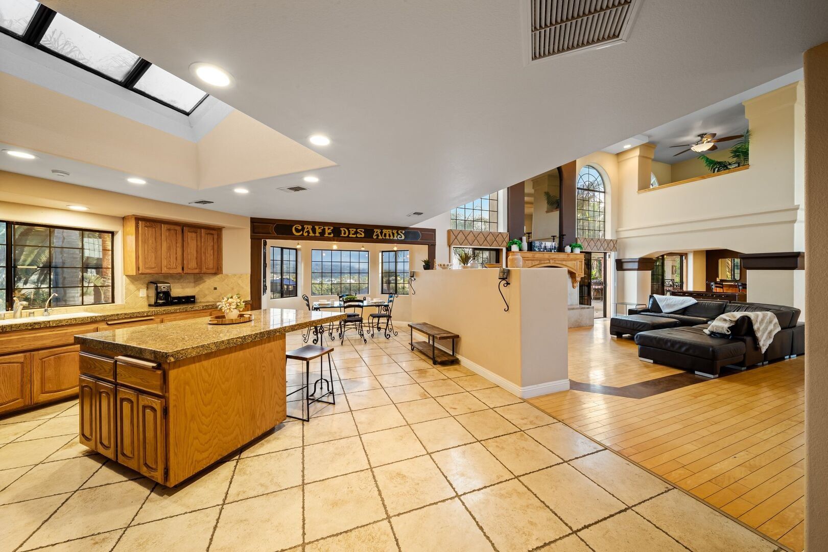 A spacious kitchen with a central island, a dining area with chairs, and a living area with a sofa.