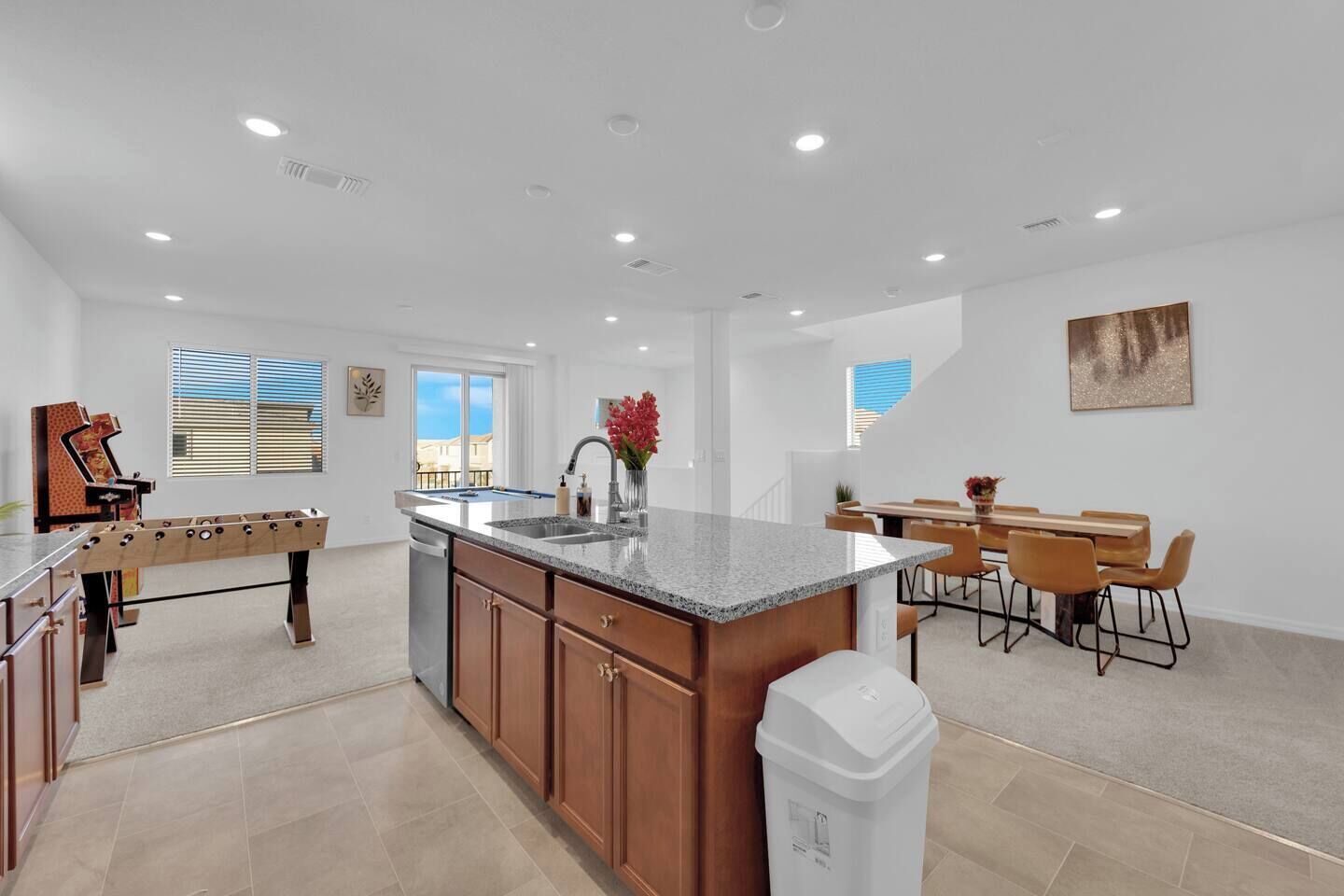 A spacious kitchen with a central island, a dining area with a table and chairs, and a view of the outside through large windows.