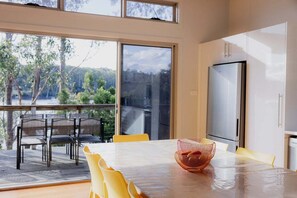 Eine moderne Küche mit einem großen Fenster, einem Esstisch mit gelben Stühlen und einem Kühlschrank.