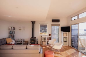 Ein modernes Wohnzimmer mit Kamin, einer Couch, einem Fernseher und einem Balkon mit Blick.