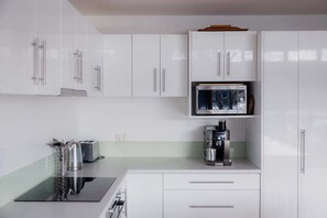 A modern kitchen with white cabinets, a microwave, a coffee machine, and a toaster. - Waterfront at Eggs and Bacon Bay "theshack@84" (Huon Valley)