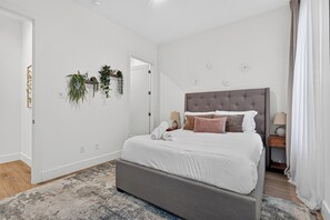 A modern bedroom with a large bed, a bedside table, a lamp, and wall-mounted plants. - Dallas Skyline Terrace Townhome (Dallas)