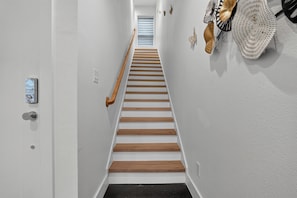 A staircase with wooden steps and a handrail, leading to a landing with a window. - Dallas Skyline Terrace Townhome (Dallas)