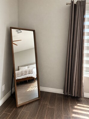 A room with a large mirror, a bed with patterned bedding, and a window with curtains. - Gilbert Oasis • Near Downtown Gilbert • King Suite • Private Yard & Grill (Gilbert)