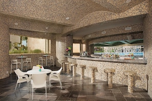 A bar area with a mosaic-tiled wall, a bar counter, and stools. - Luxury, Ocean view room at Dreams Playa Mujeres (Quintana Roo)