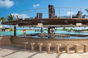 A poolside bar with a tiled floor, lounge chairs, and a view of the ocean. - Luxury, Ocean view room at Dreams Playa Mujeres (Quintana Roo)