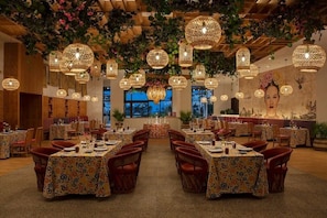Un restaurant amb taules rodones, llüsteres de vimet penjants i vista a l'exterior.