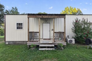 A single-story metal building with a front porch, a door, and a small window.