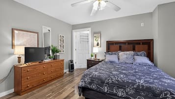 A bedroom with a bed, dresser, television, and ceiling fan.