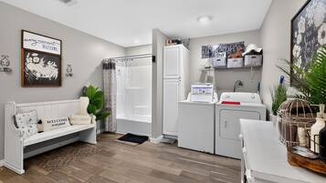 Un espace de vie compact comprenant un canapé, un lave-linge et un petit coin cuisine.