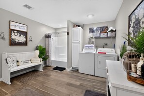 A compact living space with a sofa, a washing machine, and a small kitchen area.