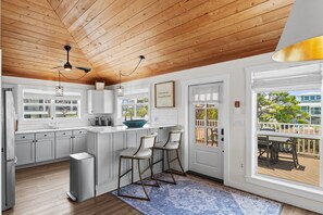 A modern kitchen with white cabinets, a blue island, and two bar stools. - Blue Me Away | Family & Pet Friendly (Port St. Joe)