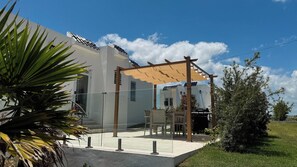 Un edificio moderno con un patio cubierto, puerta de entrada de vidrio y una parrilla visible al aire libre.