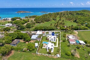A residential area with a central house surrounded by greenery, a swimming pool, and a view of the ocean. - Beach Lote Villas - Villa 1 +Pool-  Islote (Arecibo)