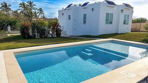 Una piscina rectangular con agua cristalina y azul, rodeada por una solana con azulejos.