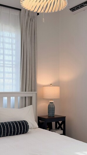 A hotel room with a bed, a bedside table with a lamp, a window with curtains, and a ceiling light fixture. - Beach Lote Villas - Villa 1 +Pool-  Islote (Arecibo)