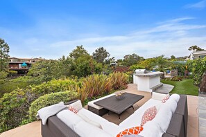 An outdoor patio with a dining table, cushioned seating, and a barbecue grill. - Sun-Drenched Coastal Haven with Private Pool (Newport Beach)