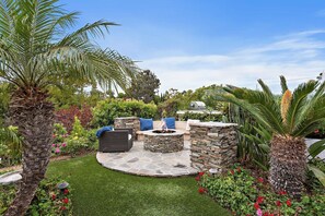 A patio area with stone seating, a fire pit, and a grill. - Sun-Drenched Coastal Haven with Private Pool (Newport Beach)