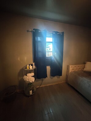 Una camera da letto con finestra, comodino e articoli da toilette.