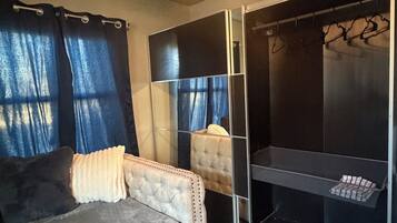 A bedroom with a bed, a wardrobe, and a mirror.