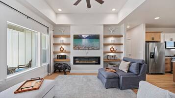 A modern living room with a fireplace, a sofa, a coffee table, and a television.