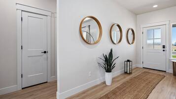 A hallway with white walls, wooden flooring, and three round mirrors on the wall.