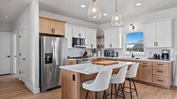 A modern kitchen with stainless steel appliances, white cabinetry, and a central island with bar stools.