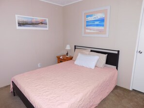 A bedroom with a bed, a nightstand, a lamp, and two framed pictures on the wall. - Affordable 3 bedroom Beach House in Murrells Inlet (Murrells Inlet)