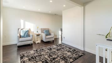 Una habitación amplia con dos sillones, una mesita y un tapiz estampado.