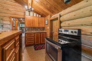 A kitchen with wooden cabinets, a black stove, and a tiled backsplash.