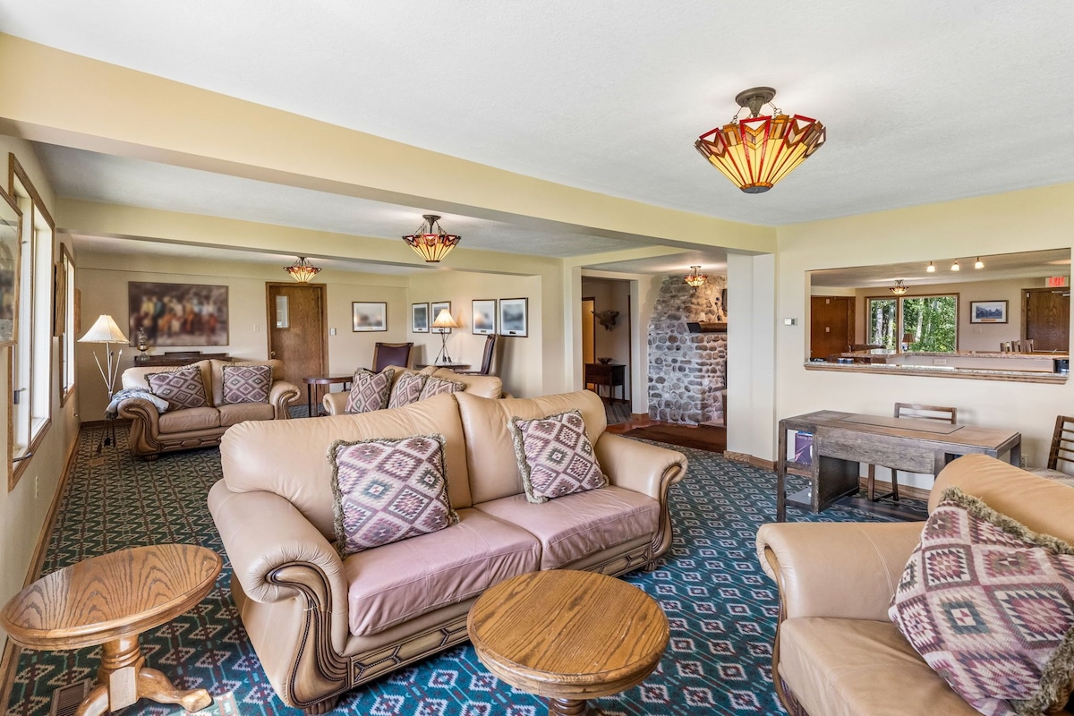 A spacious living area with a large sofa set, a dining table, and a stone accent wall.