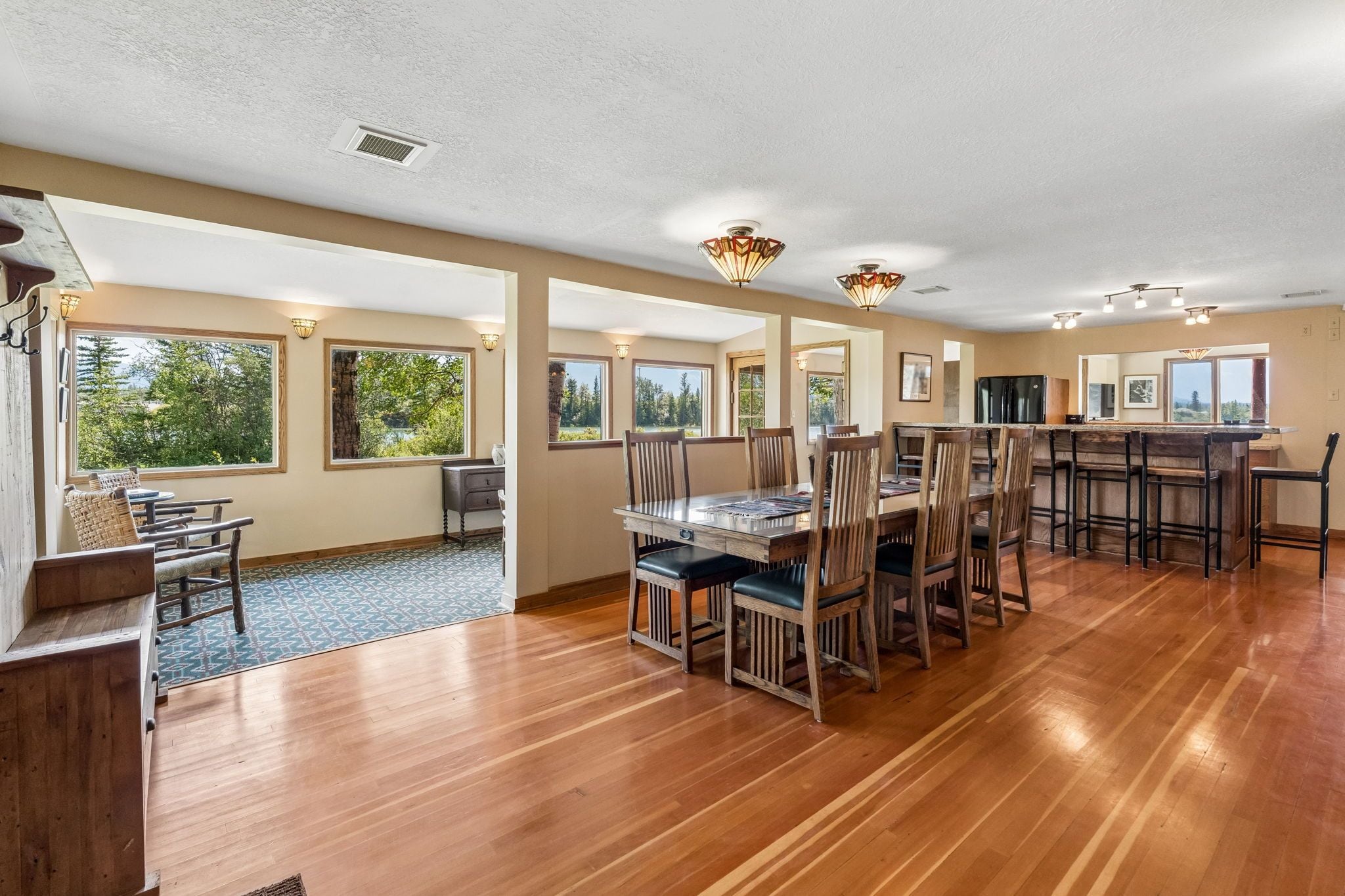 A spacious dining area with wooden flooring and a large table surrounded by chairs.