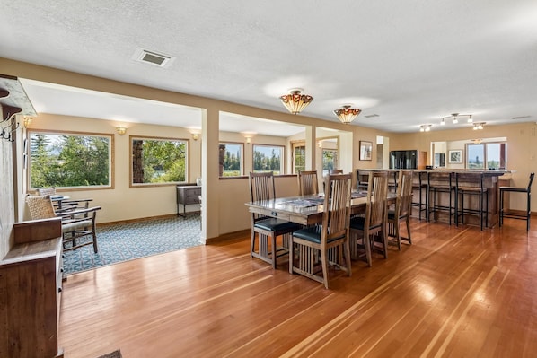 A spacious dining area with wooden flooring and a large table surrounded by chairs.