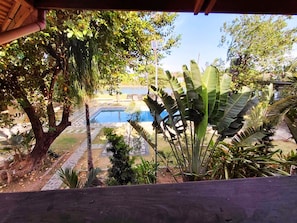 A pool area with surrounding vegetation and a clear sky. - RiverCoves Resorts (Bulacan)