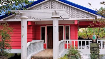 A red house with a white porch and a blue roof.
