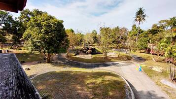 A landscaped garden with a curved pathway, trees, and a small pond.