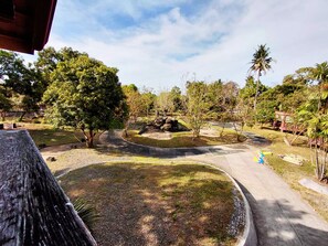 A landscaped garden with a curved pathway, trees, and a small pond.