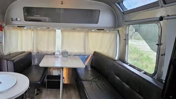 A compact RV interior with a dining area, seating, and a skylight.