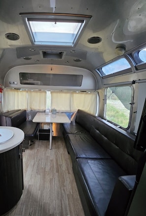 A compact RV interior with a dining area, seating, and a skylight.