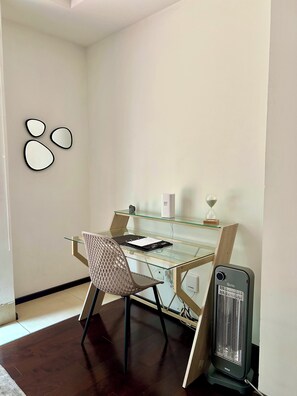 A modern office space with a glass desk, a chair, a standing heater, and a wall-mounted clock. - Apartment just steps from the Angel of Independence / Reforma, with parking (Ciudad de México)