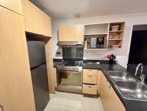 Eine kleine Küche mit Kühlschrank, Herd, Mikrowelle und Spüle.
