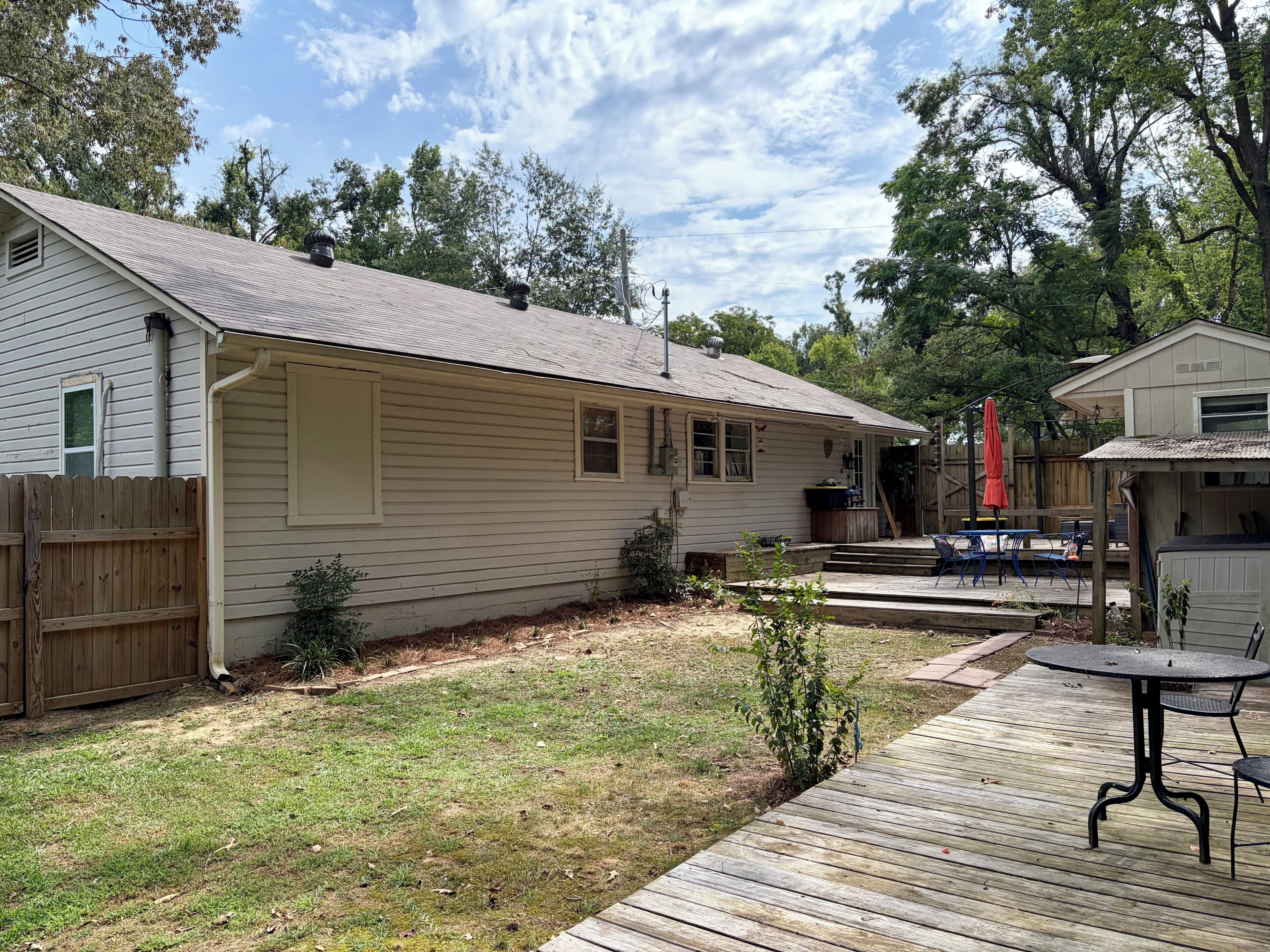 A residential property with a detached garage, a covered patio area with outdoor furniture, and a wooden deck.