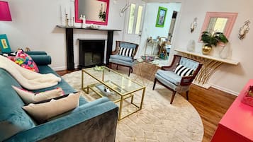 Un salon avec un canapé bleu, une table basse en verre et une cheminée.