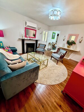 A living room with a blue sofa, a glass coffee table, and a fireplace.
