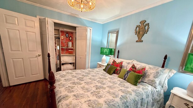 A bedroom with a bed, a wardrobe, a mirror, and a chandelier.