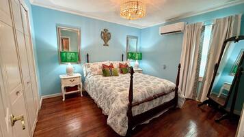 Un dormitorio con una cama con dosel, un candelabro, una mesita de noche con lámpara y un espejo.