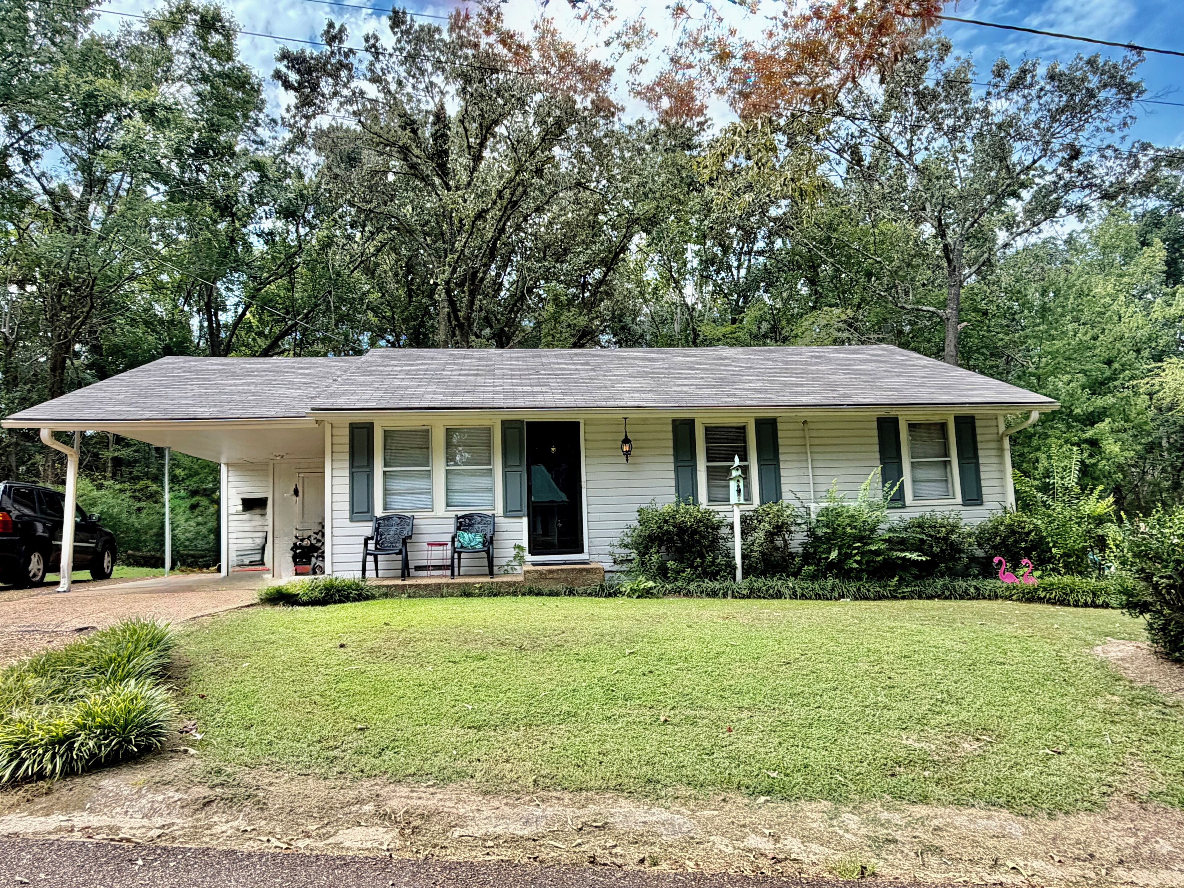 A single-story house with a porch, a small lawn, and a car parked in front.