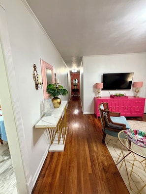 A hallway with a dining table, chairs, a pink cabinet, a television, and a plant. - Cozy  vintage style 3 bedroom  1 bath home in beautiful Water Valley (Water Valley)