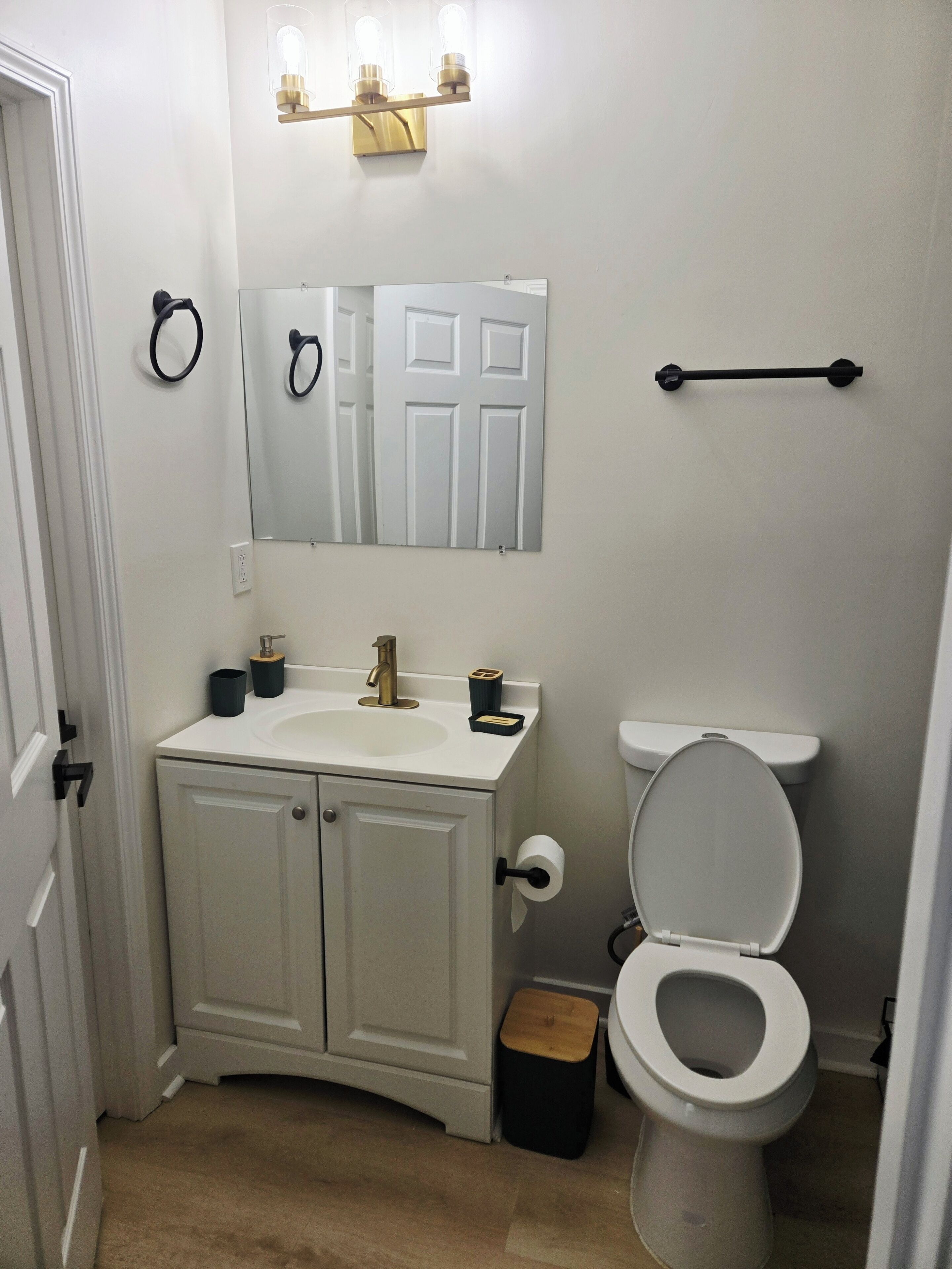 A bathroom with a white sink, a toilet, a mirror, and a towel rack.